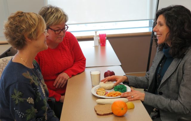 Three women discussing a nutritional plate of food